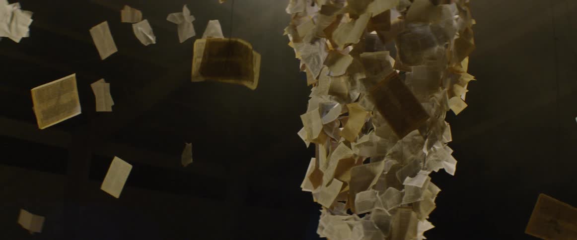 An art installation containing postcards and pages of text suspended from the ceiling