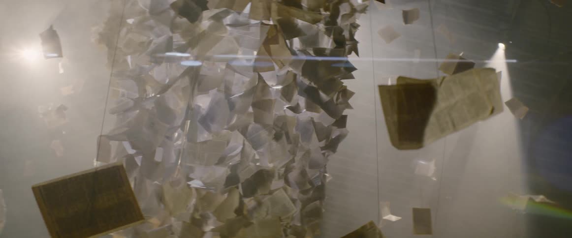 Pages hanging from the ceiling with strings with lights in the background