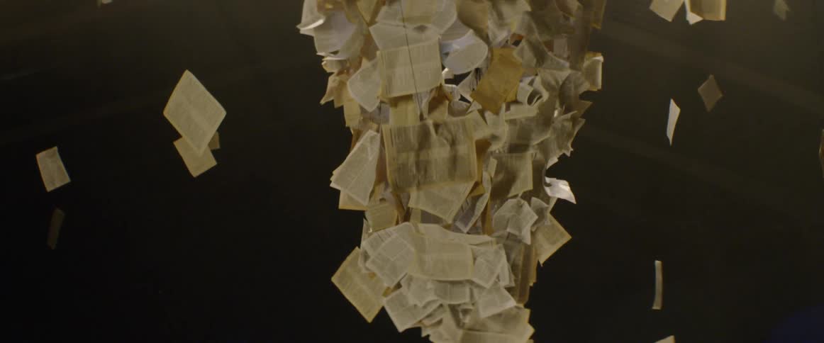 Book pages hang on wire from the ceiling floating around a paper art sculpture