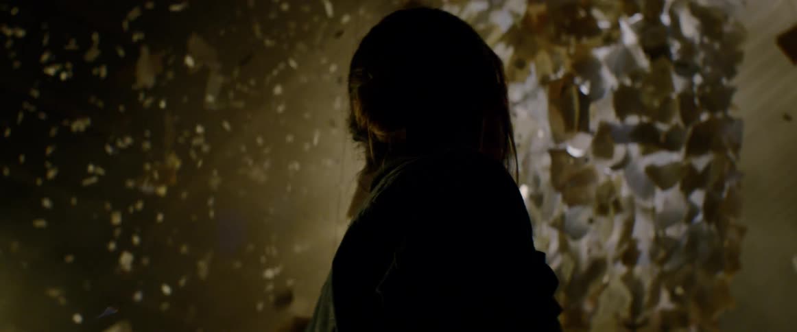 The silhouette of a woman looking at a light and paper art installation with confetti falling