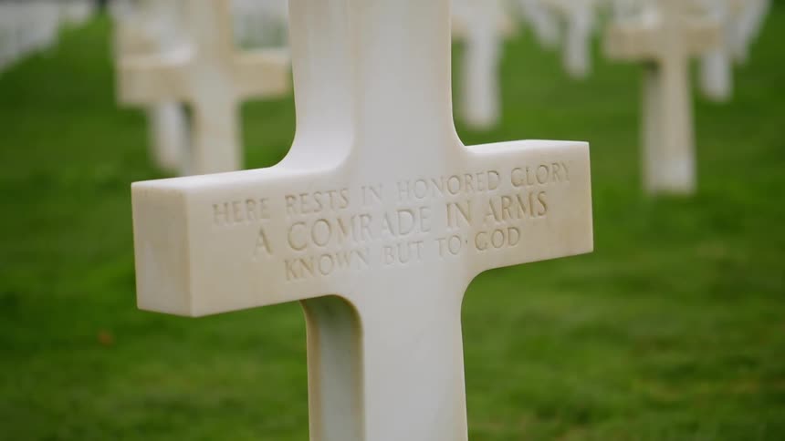 White stone crosses form rows among green grass of cemetery