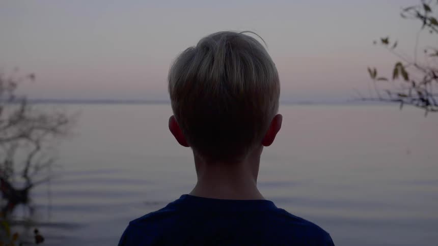 A footage of a boy staring at the lake