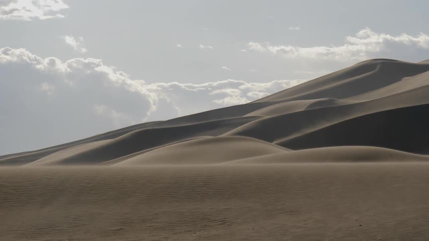 Wind blows the sand from the surface of the dunes