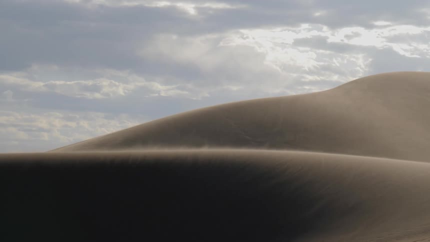 Wind blows the sand from the surface of the dunes