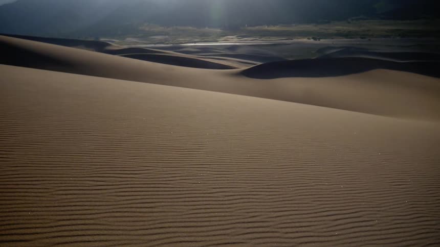 Wind blows the sand from the surface of the dunes