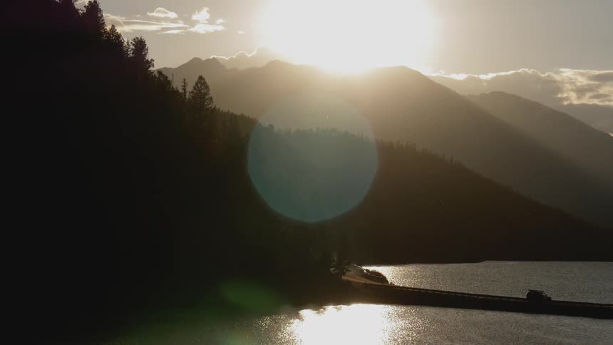A van drives across a road dividing a lake as the sun rises