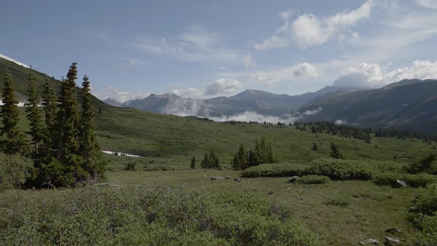 A still mountain scene with lush vegetation under a mainly blue sky