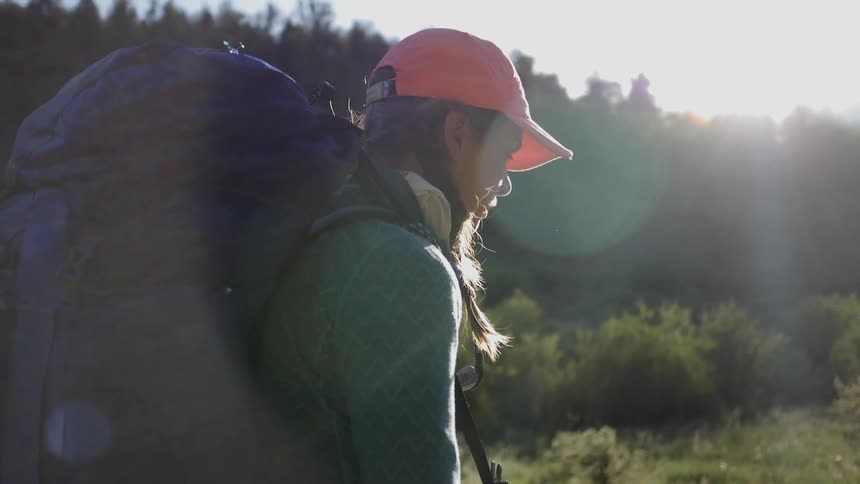 A young woman hiking while carrying a huge backpack