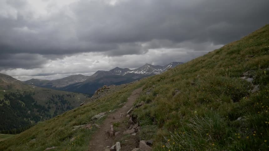 A scenery of a grassland on the mountain at the cloudy day