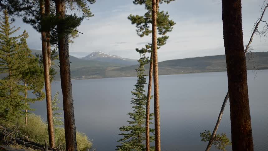 Conifer dots bank of lake surrounded by mountains