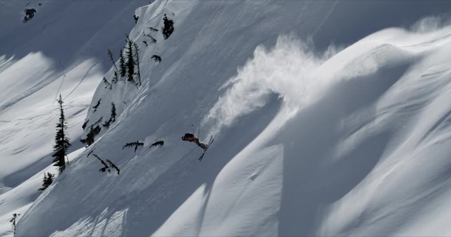 A person is skiing down a mountain slope and does a back flip