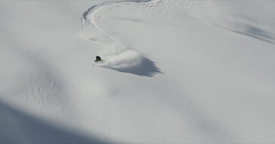 A man skiing downhill on the snowy mountain