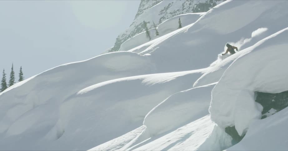 A person skis down a mountain full of snowy hills