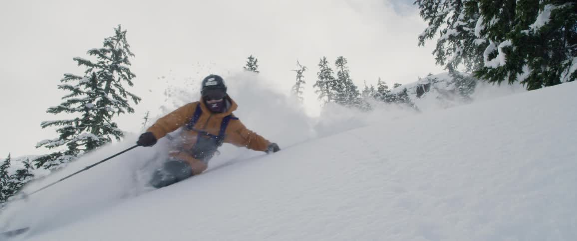 Skier races down slope kicking up snow