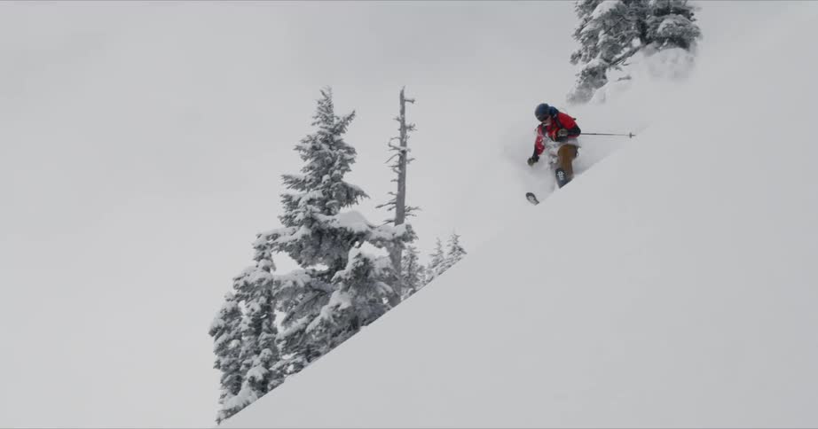 A skier glides down a steep snowy mountainside