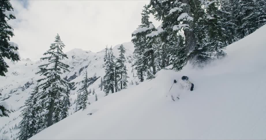 A skier travels swiftly down a steep mountainside covered in thick snow