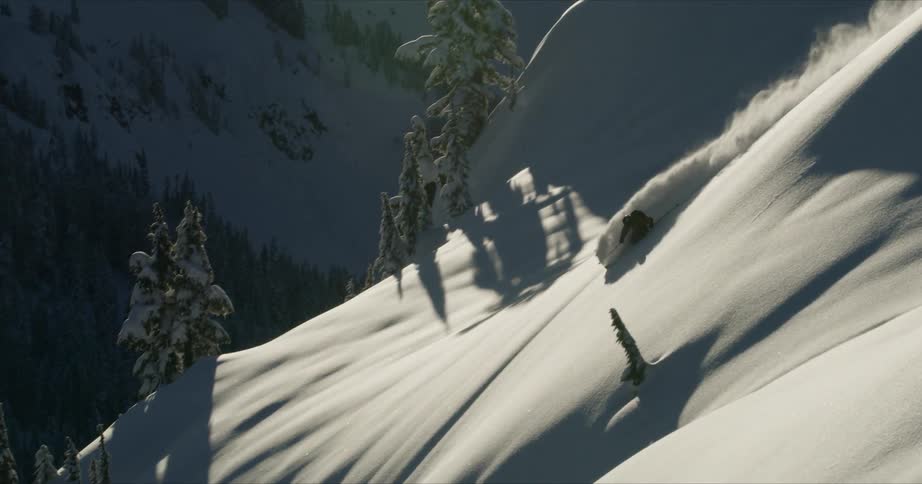 A skier speeds down a steep snowy mountainside