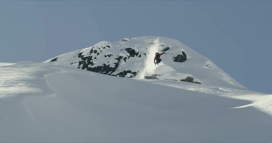 A skier launching him or herself off a rock and landing on a slope
