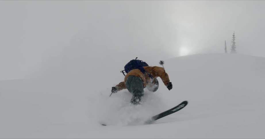 A skier spins and crashes while skiing down a snowy mountainside