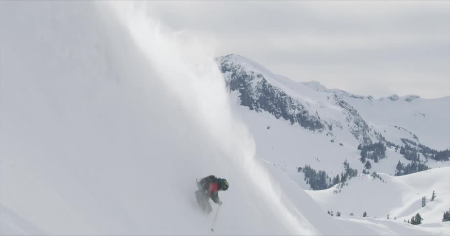 A person skis down a hill with a cloud of snow following them