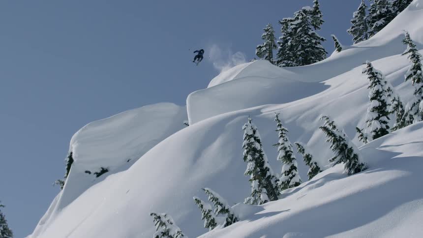 A skier skiing downhill on snow doing ski tricks