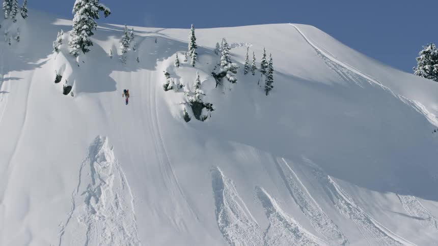 A person makes a large flip in the air and skis down a steep mountainside