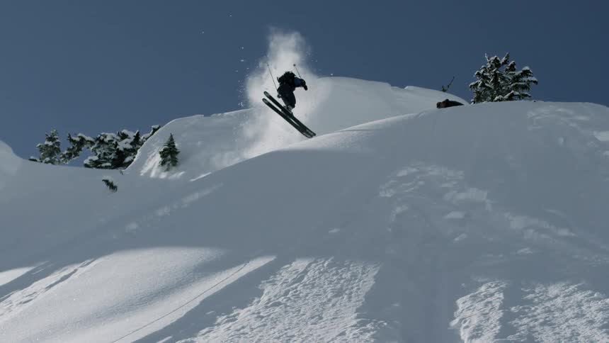 A skier spins in the air and lands backwards in the snow