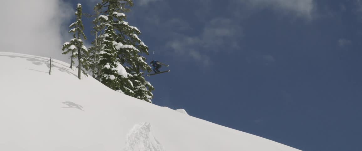 A skier doing a spin in the air before landing on a slope