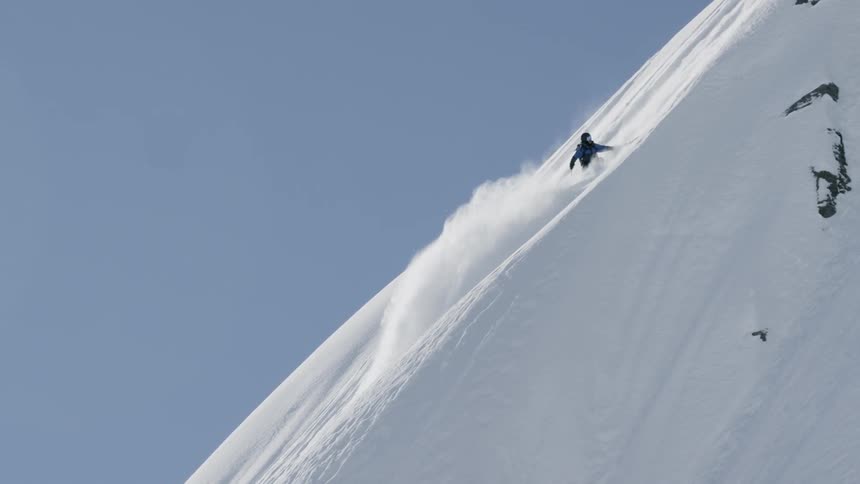 A person skis down the very steep slope before stopping to hold on