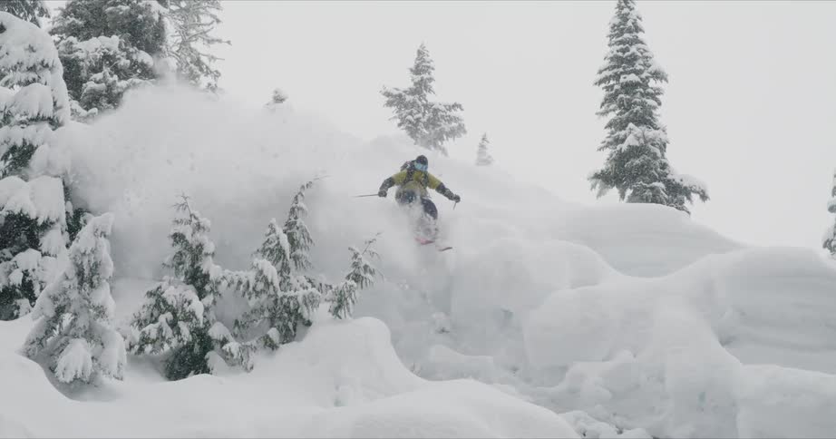 A skier jumps over drifts of snow on a mountainside
