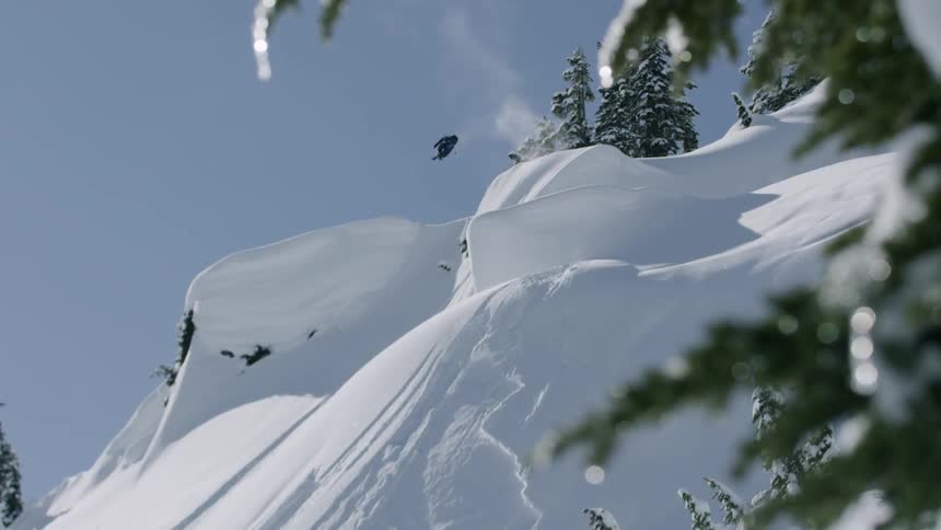 Skier jumps and spins down steep slope