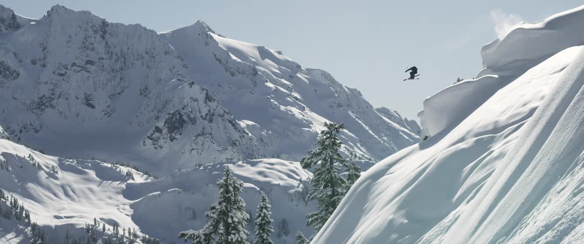 A man jumping from top of the mountain with ski