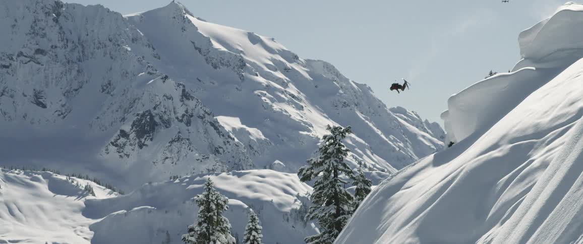 A man jumping from the mountain peak with snowboard