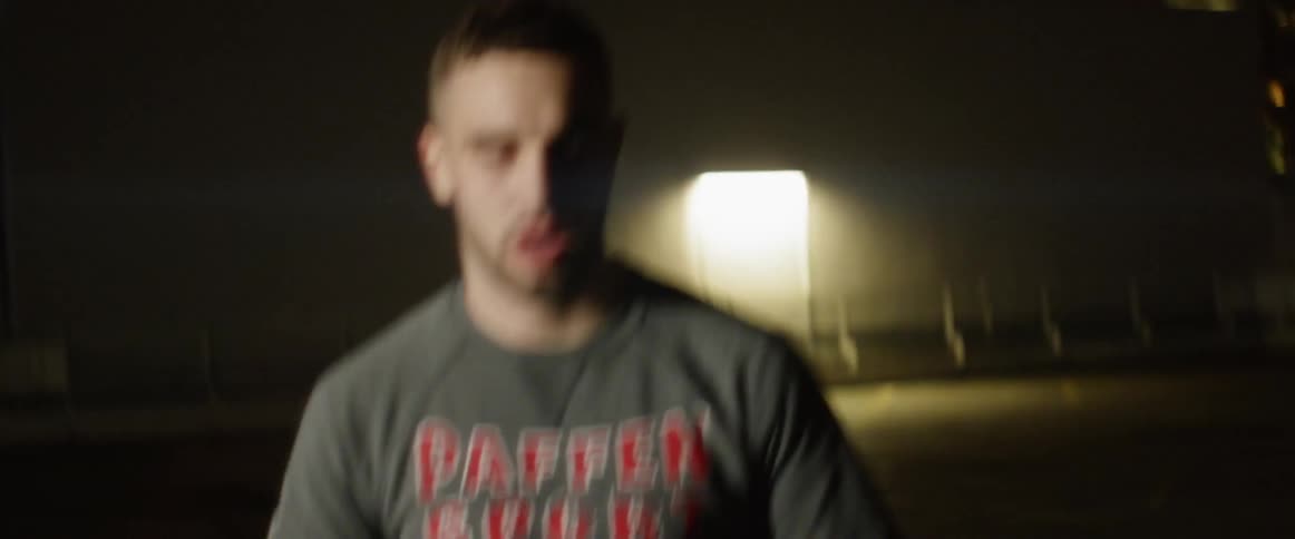 A white male is using a jump rope to exercise outside at night