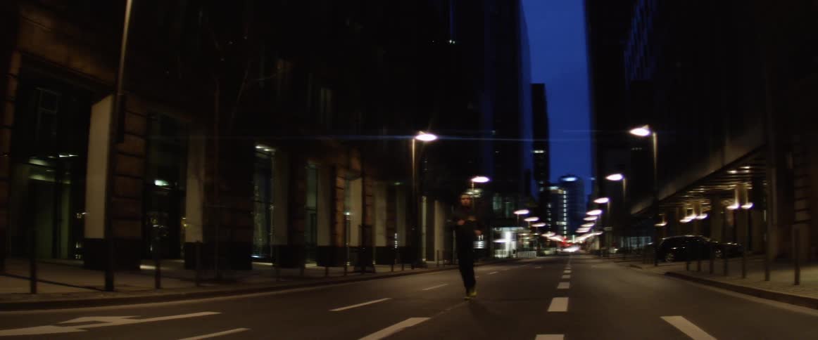 A young man jogs along a darkened city street at night time