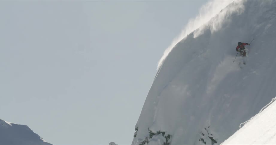 A man is skiing downhill a mountain covered in snow