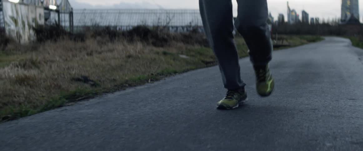 Man runs along asphalt road in the countryside on a cloudy day