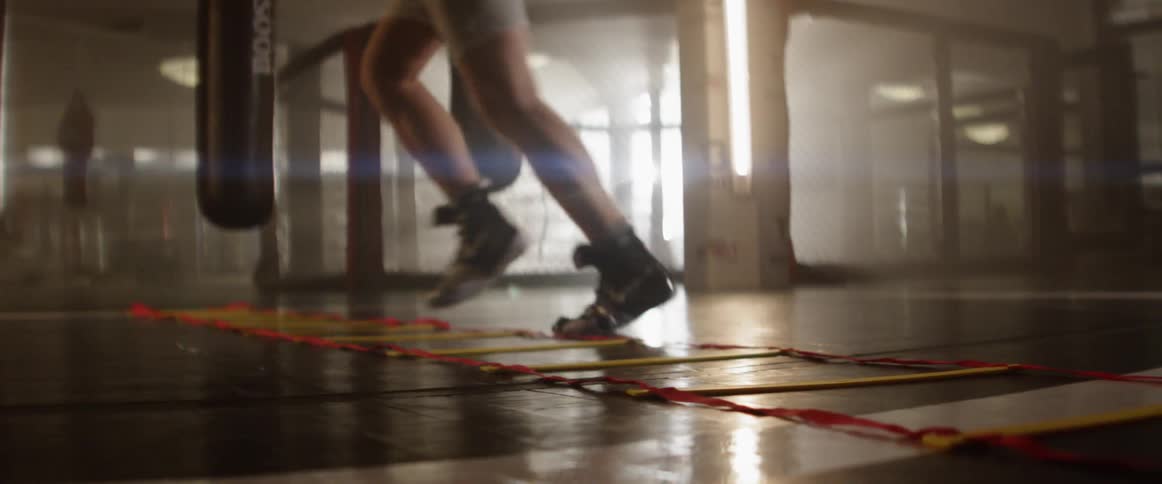 A boxers legs and feet as he works his way through a ladder speed and agility drill in the gym