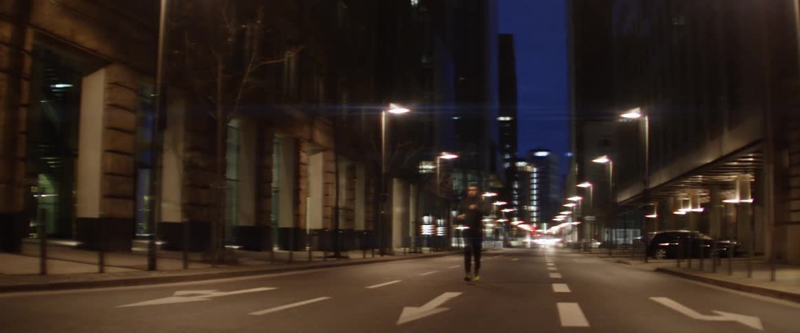 Man jogs down center of street downtown at night