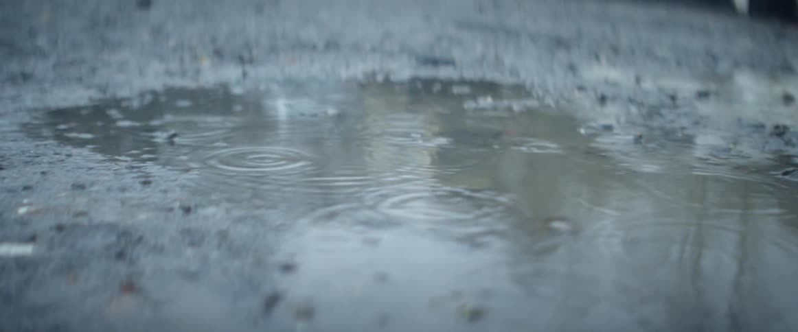 A light rain makes waves in a small puddle