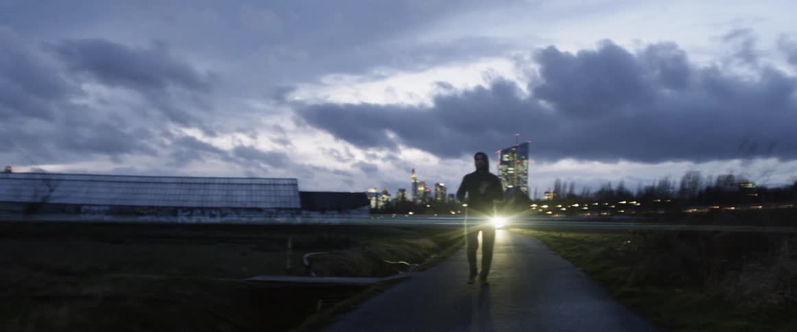 Man jogs along single lane road through fields near busy highway