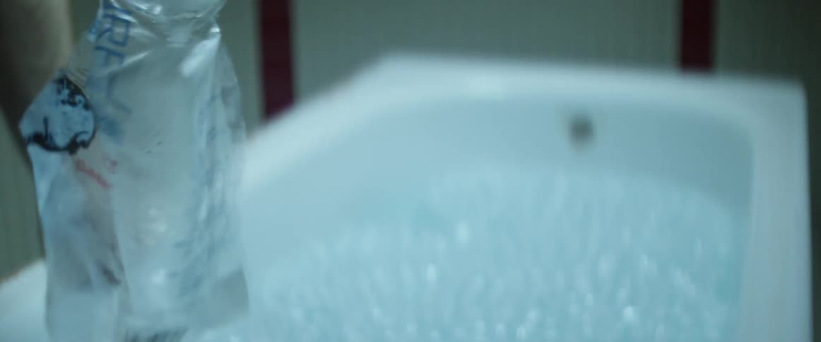 A white man dumps ice into a full bathtub