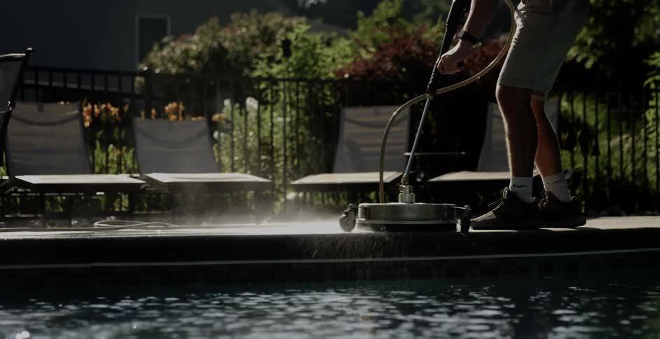 A person uses a large cleaning machine to clean a poolside patio