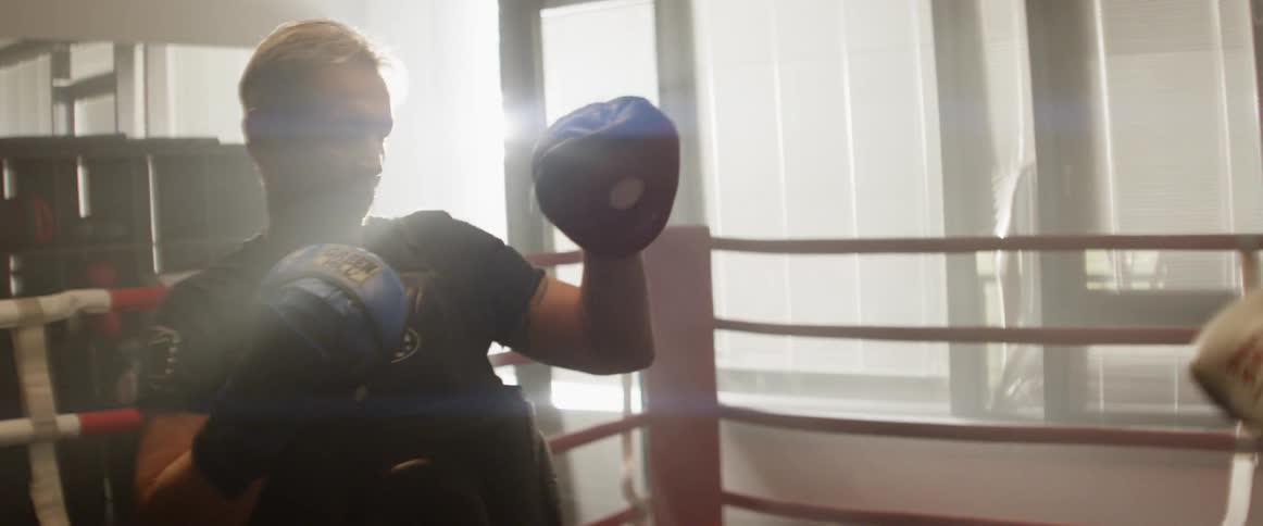 Two men practice boxing in a boxing ring inside a gym