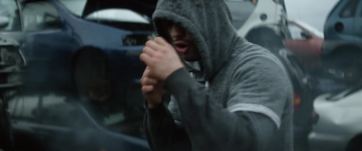 Man wearing a hoodie boxes in the junkyard