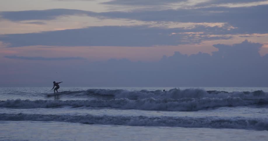 A man surfing on the beach at the dawn