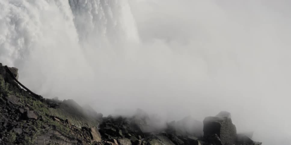 Mist covers the rocks as white water rushes down a waterfall