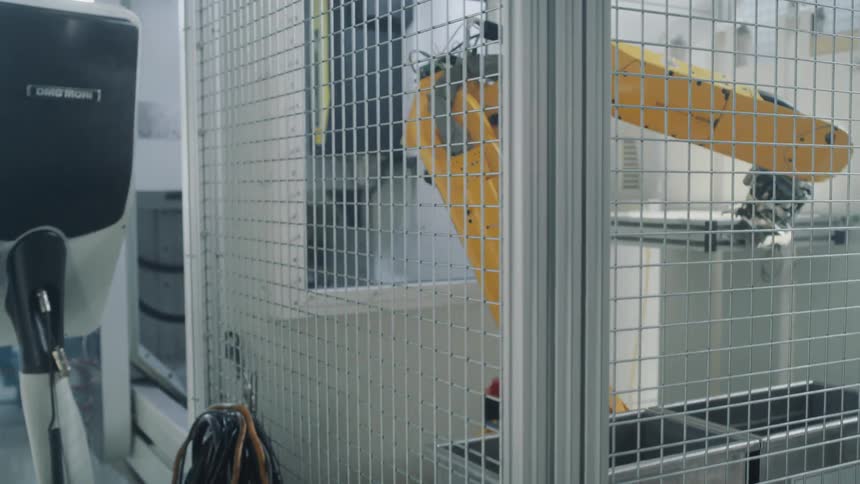 Industry robot in a protective cage works on something