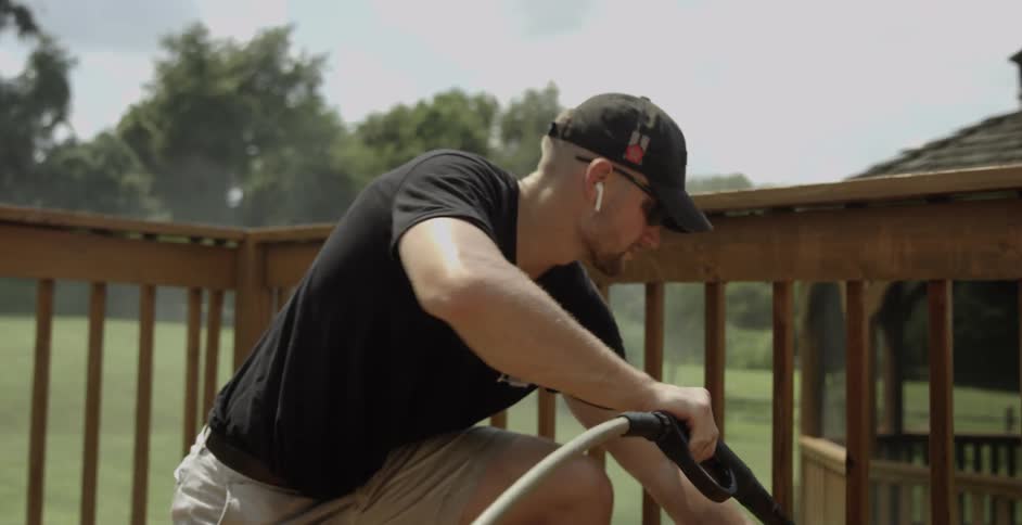 A man cleans his deck with a power washer