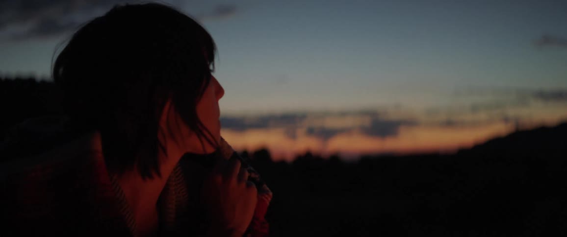 A young woman contemplatively thinking at the camp fire